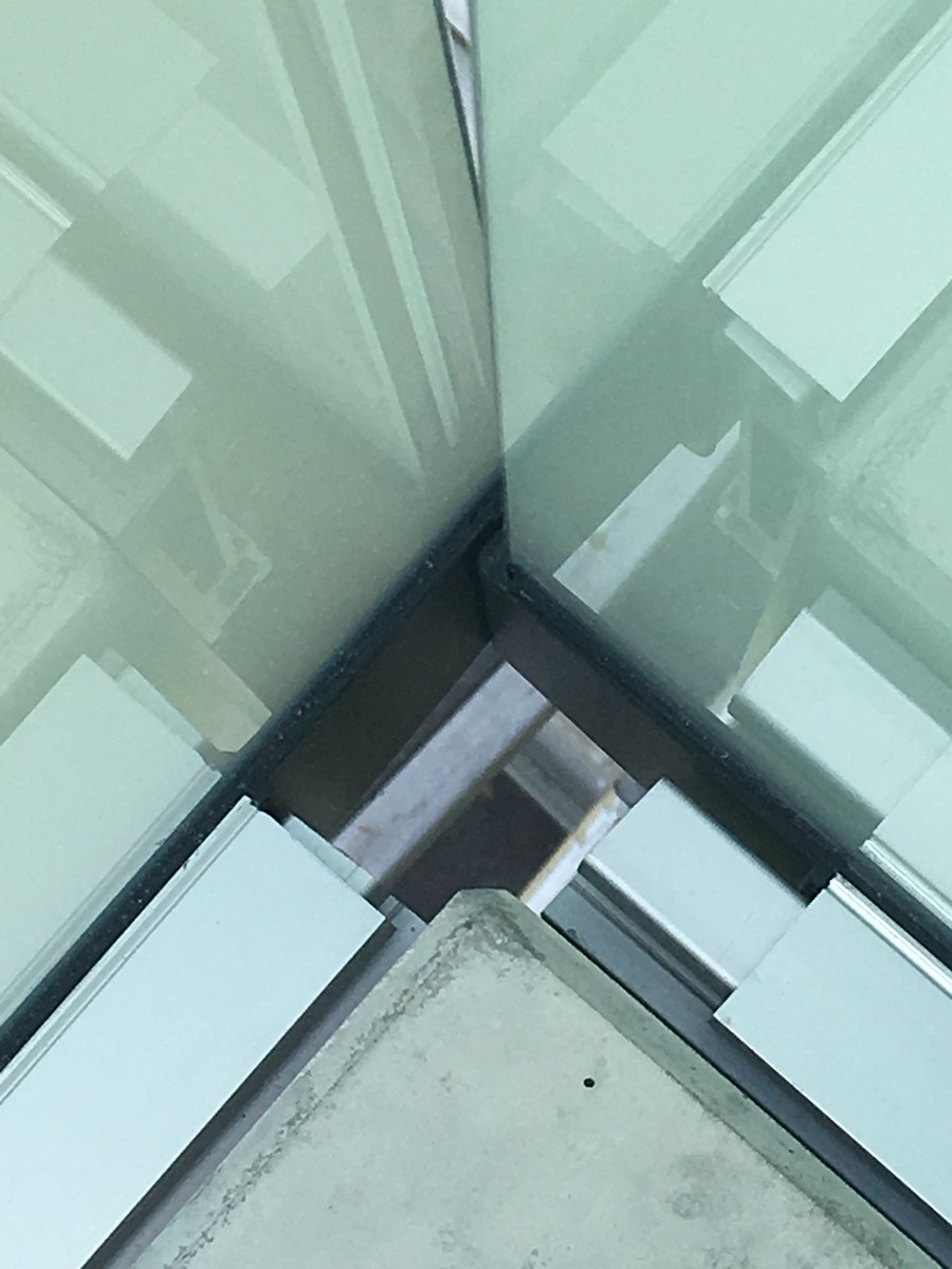 Detail der Eckverbindung eines satinierten Ganzglasgeländers an der Basis – Handwerk Wandlitz