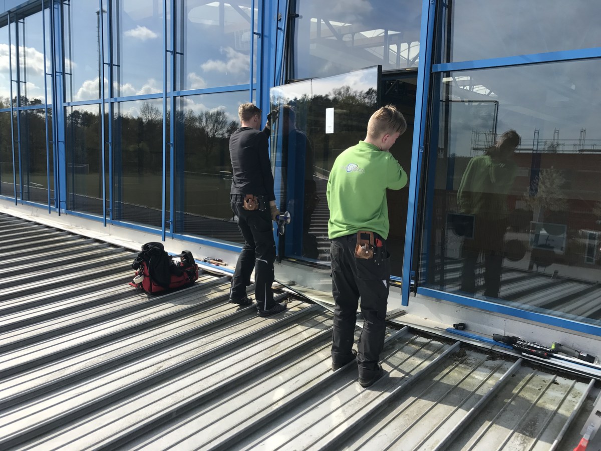 Montage einer großen Glasfassade mit blauen Rahmen am Gebäude – Glasermeisterbetrieb Wandlitz